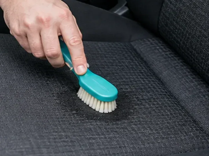 Cepillado suave de una mancha en un asiento de tela del coche